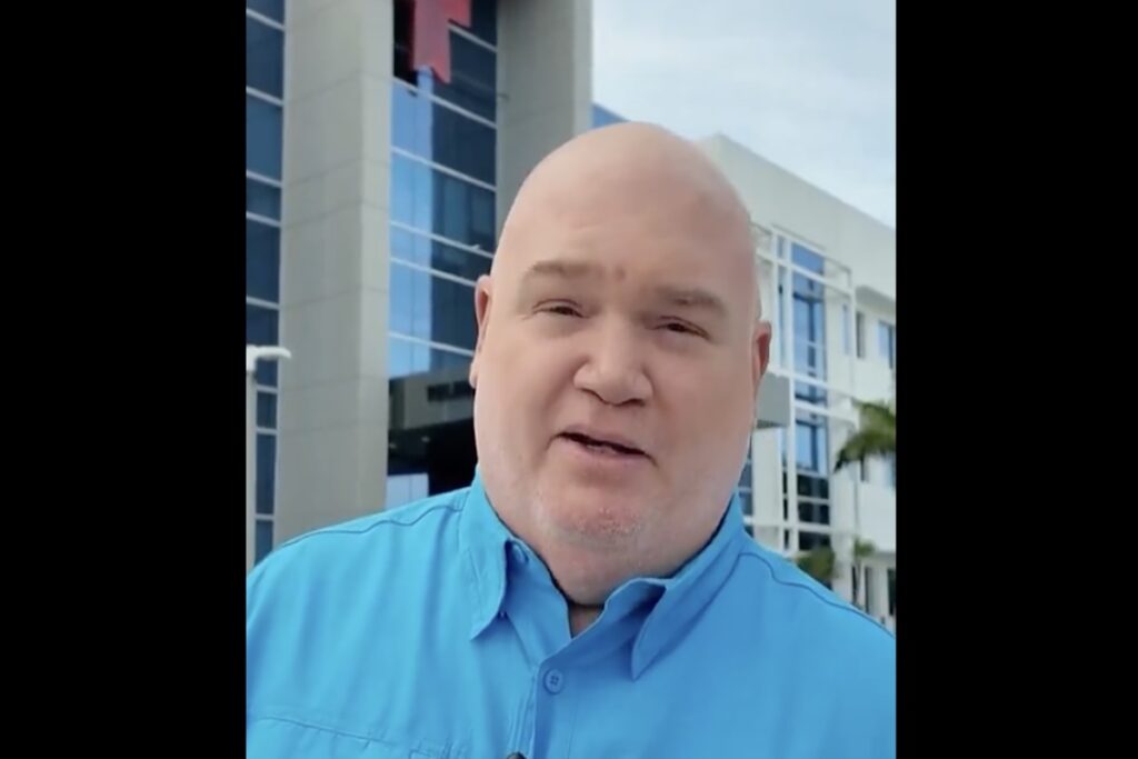 Hombre calvo en camisa azul frente a edificio moderno